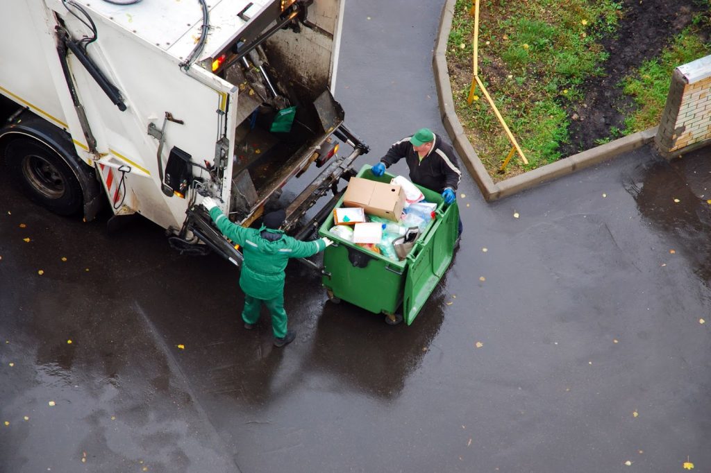 A garbage truck with workers loading trash during garbage cleanup and junk removal services