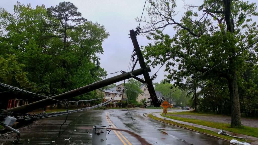 A downed power pole on a rain-soaked street, highlighting storm damage and the need for preparedness and restoration efforts.