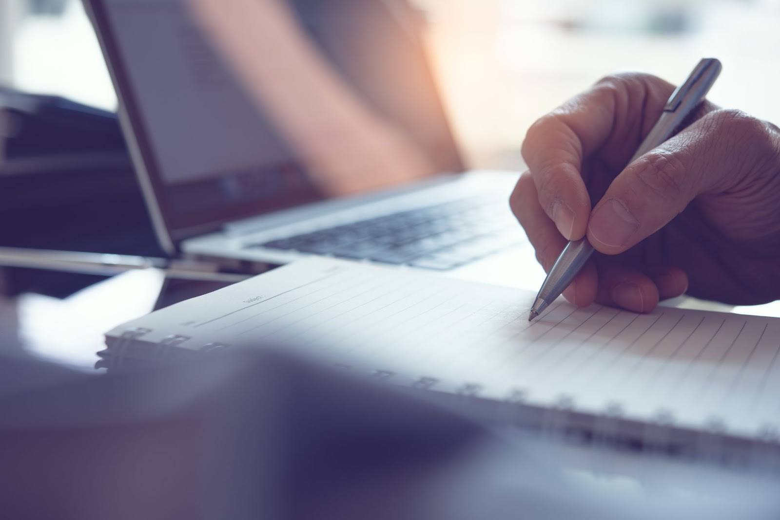 Businessman notes in a notebook beside a laptop, highlighting the urgency of water damage restoration after a fire incident.