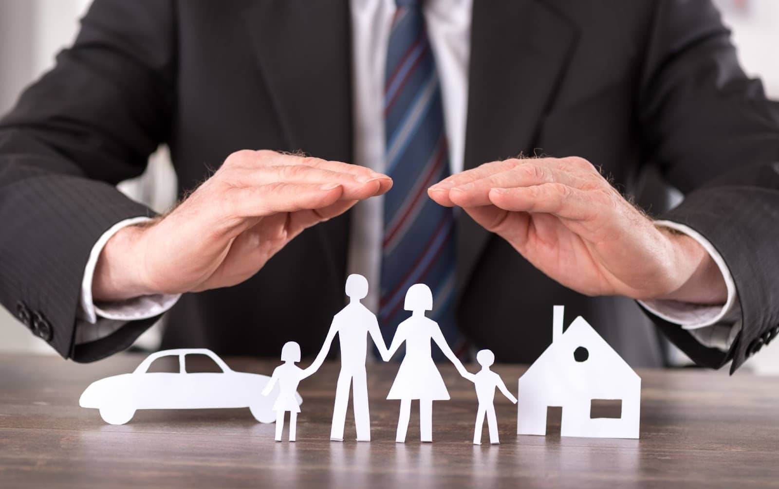 A man in a suit holds paper cutouts of a family and car, symbolizing storm damage and disaster insurance coverage.
